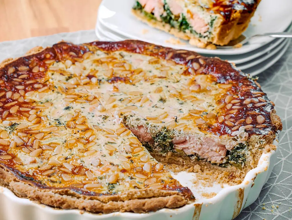 Ein Stück Lachs-Spinatkuchen mit knusprigem Teig und saftiger Füllung, serviert auf einem Teller.