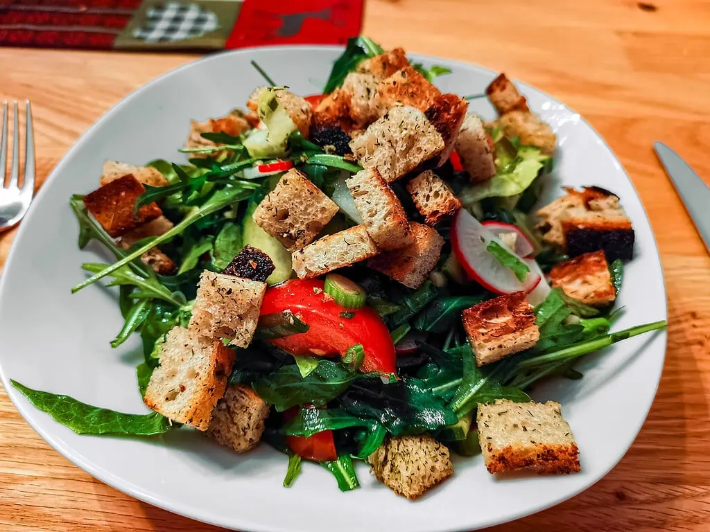 Italienischer Brotsalat (Brotsalat mit Rucola und Tomate) piccata vom schwein