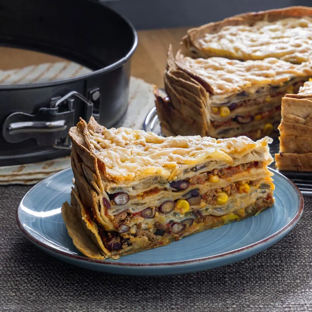 Mexikanische Tortilla Lasagne auf einem Teller, gut geschichtet mit Bohnen und Käse.